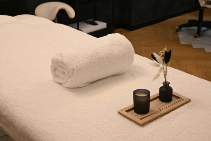 A clean and welcoming massage table prepared for a full body spa day with a folded white towel and a small decorative tray.