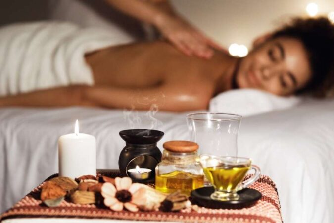 Aromatic candles, massage oils, and wellness accessories arranged on a tray during a luxury spa day.