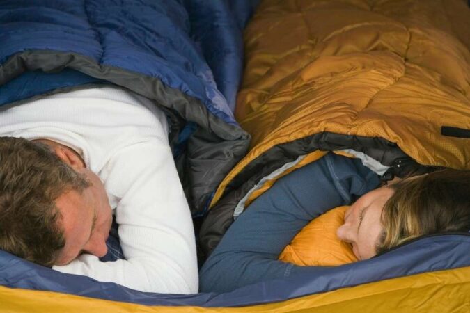 A couple sleeping comfortably in a tent inside warm sleeping bags.